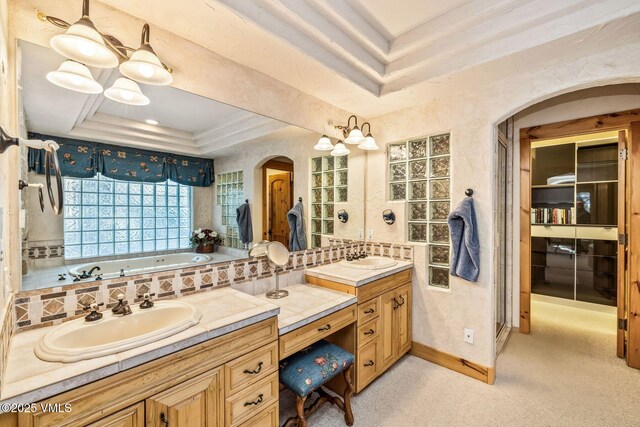 bathroom with vanity, a tub to relax in, decorative backsplash, and a tray ceiling