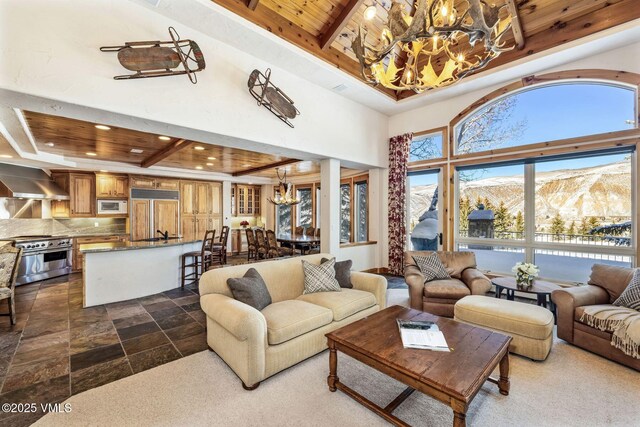 living room featuring a mountain view, wooden ceiling, a chandelier, and a tray ceiling