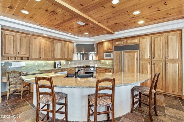 kitchen featuring a kitchen island with sink, wall chimney range hood, wooden ceiling, and built in appliances