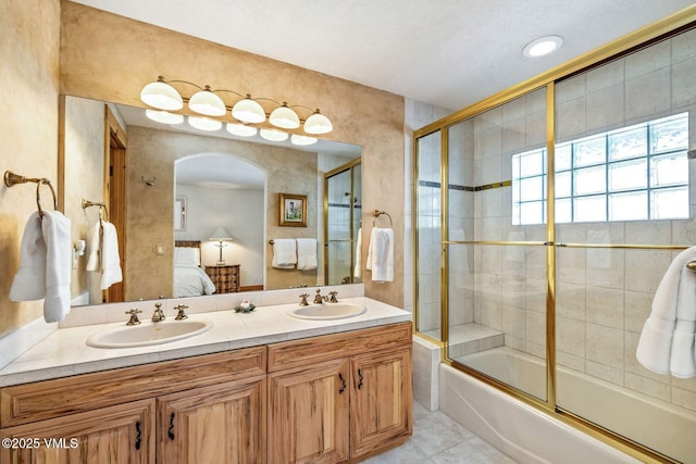 bathroom featuring enclosed tub / shower combo, tile patterned floors, and vanity