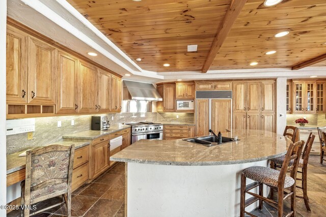 kitchen featuring wall chimney range hood, built in appliances, wood ceiling, and decorative backsplash