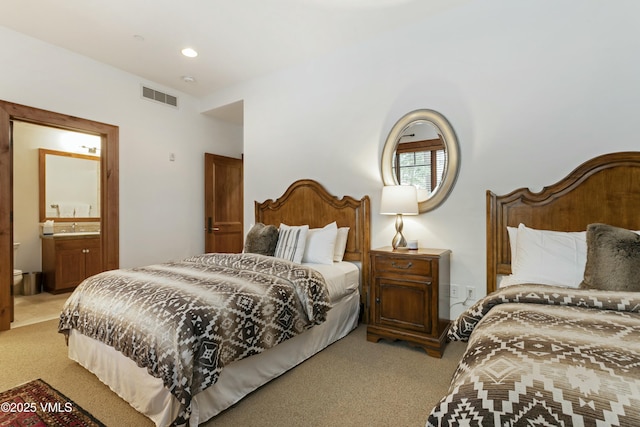 bedroom featuring ensuite bathroom, sink, and light carpet