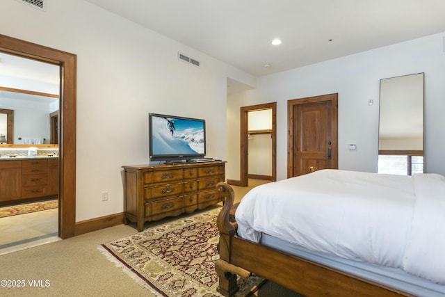 bedroom featuring connected bathroom and light carpet