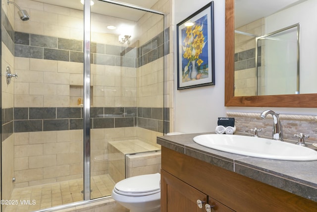 bathroom with vanity, toilet, a shower with shower door, and decorative backsplash