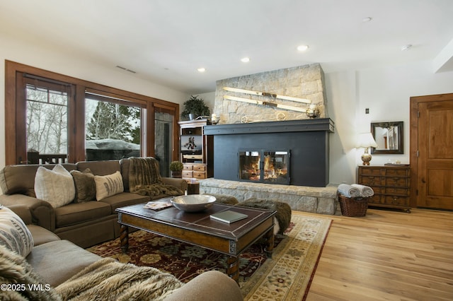 living room featuring wood-type flooring and a stone fireplace