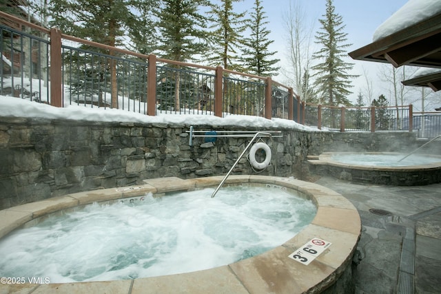 snow covered pool featuring an in ground hot tub