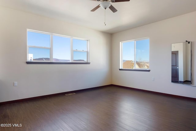 empty room featuring visible vents, baseboards, wood finished floors, and a ceiling fan