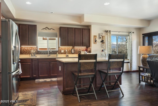 kitchen featuring a sink, backsplash, stainless steel fridge with ice dispenser, and light countertops