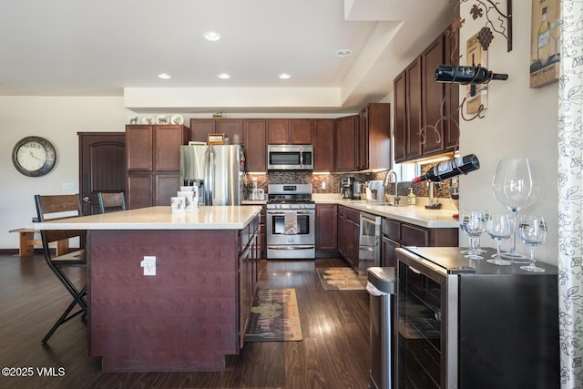 kitchen with backsplash, light countertops, dark wood-style floors, stainless steel appliances, and a sink