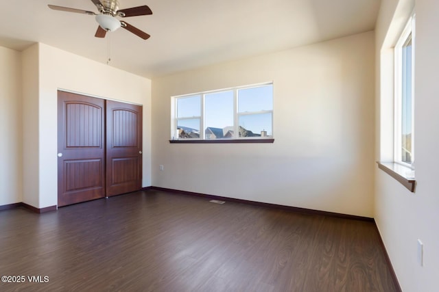 unfurnished bedroom featuring a closet, baseboards, ceiling fan, and dark wood-style flooring