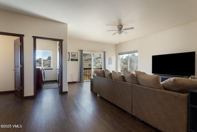 living area featuring baseboards, dark wood-type flooring, and a ceiling fan