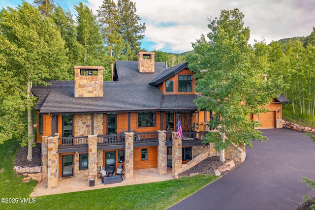 25 W Timber Draw Dr, Edwards, CO 81632 - view of front of house with stone siding, a chimney, a patio, and a balcony