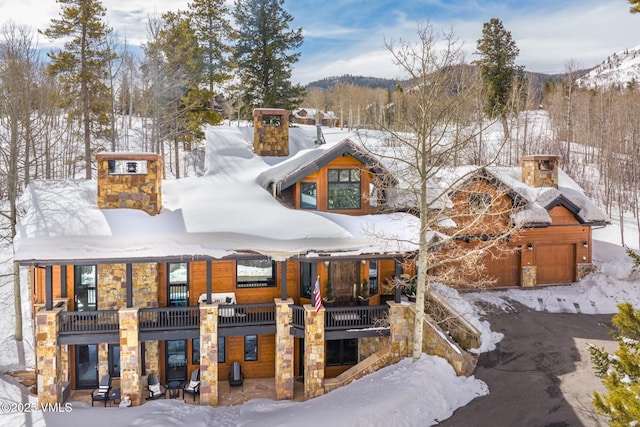 25 W Timber Draw Dr, Edwards, CO 81632 - view of front of house with a chimney, stone siding, a garage, a mountain view, and a balcony