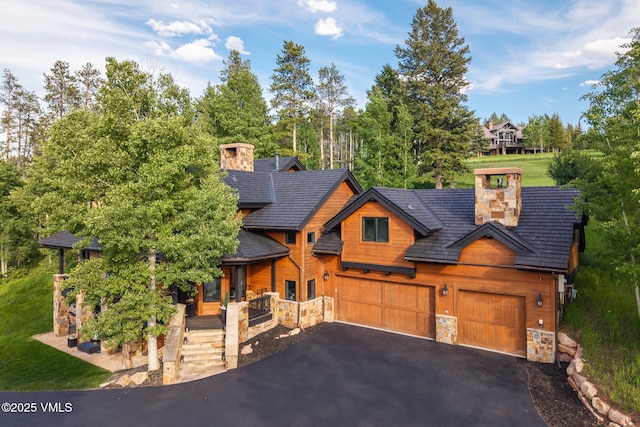 25 W Timber Draw Dr, Edwards, CO 81632 - view of front of home with stone siding, asphalt driveway, covered porch, a chimney, and a garage