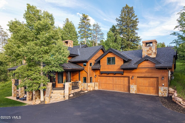 25 W Timber Draw Dr, Edwards, CO 81632 - view of front of house featuring stone siding, asphalt driveway, a chimney, and an attached garage