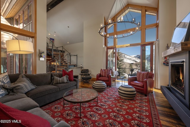 living area with wood finished floors, a lit fireplace, high vaulted ceiling, a mountain view, and a notable chandelier