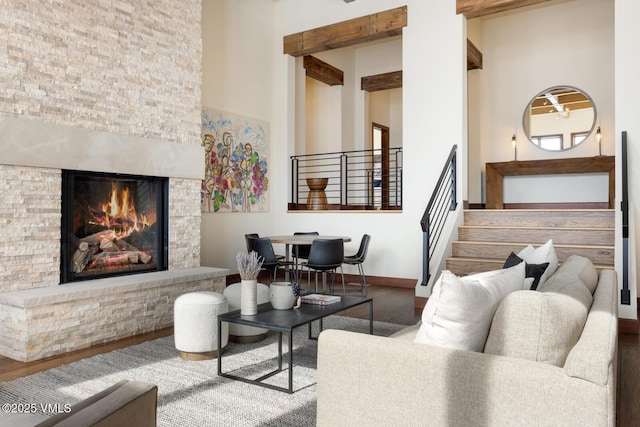 living room with baseboards, wood finished floors, stairs, a high ceiling, and a fireplace