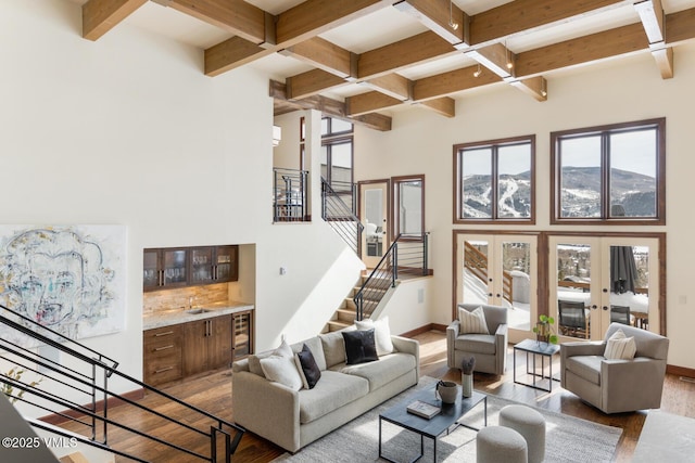 living room featuring wine cooler, wood finished floors, baseboards, stairs, and french doors