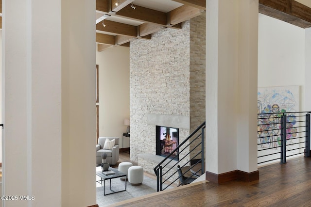 interior space featuring a fireplace, a towering ceiling, baseboards, beam ceiling, and dark wood-style floors