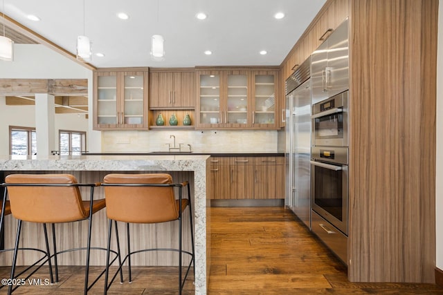 kitchen with modern cabinets, glass insert cabinets, light stone counters, and a sink