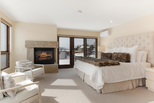 bedroom with light colored carpet, access to outside, an AC wall unit, and a glass covered fireplace