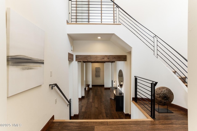 stairs with a high ceiling, wood finished floors, and baseboards