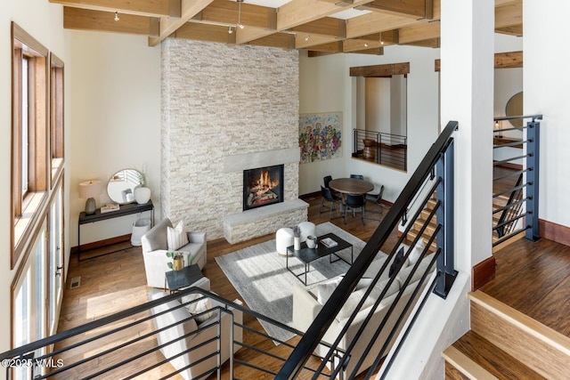 living area with beamed ceiling, a fireplace, and wood finished floors