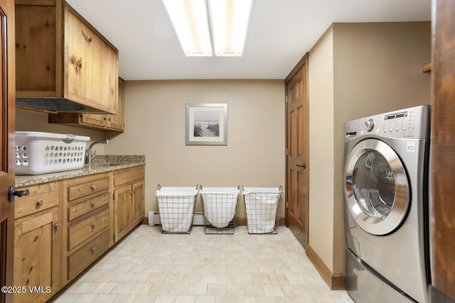 washroom featuring washer / clothes dryer, cabinet space, a sink, and baseboards