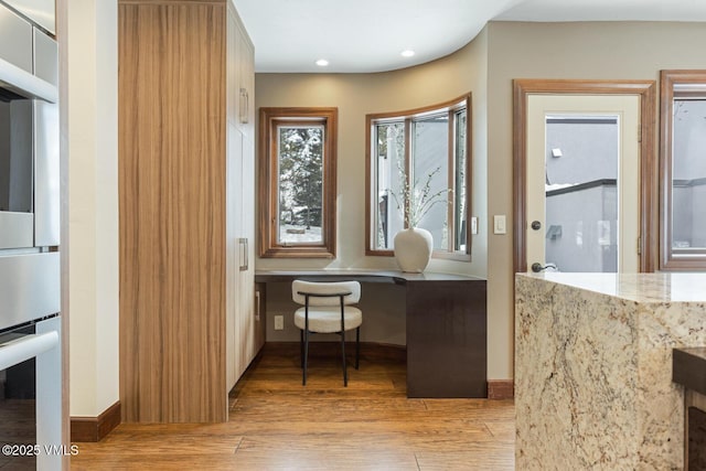 home office featuring light wood-type flooring, baseboards, built in desk, and recessed lighting