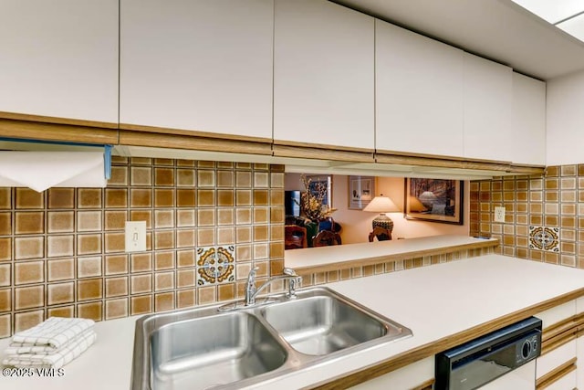 kitchen with dishwasher, decorative backsplash, a sink, and light countertops