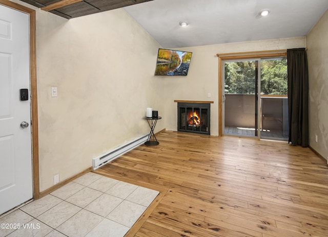 1050 W Beaver Creek Blvd Unit 201, Avon, CO 81620 - unfurnished living room with a baseboard heating unit, a lit fireplace, hardwood / wood-style floors, and recessed lighting