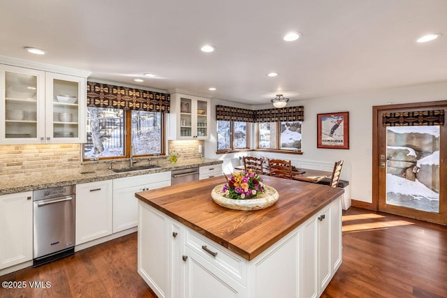 kitchen with a sink, dark wood finished floors, butcher block counters, decorative backsplash, and dishwasher