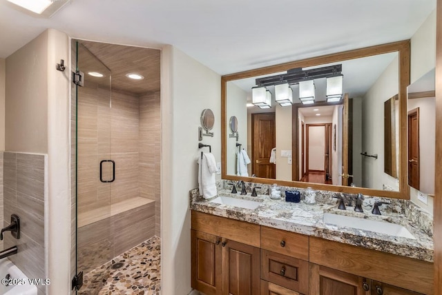 bathroom featuring double vanity, a shower stall, and a sink