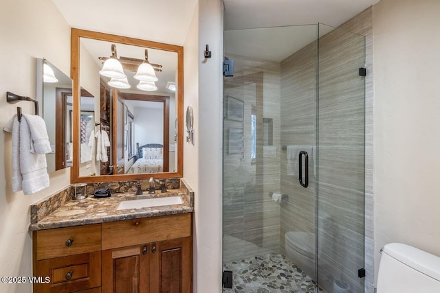 ensuite bathroom with connected bathroom, vanity, a shower stall, and toilet