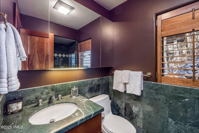 half bathroom with toilet, tile walls, and vanity