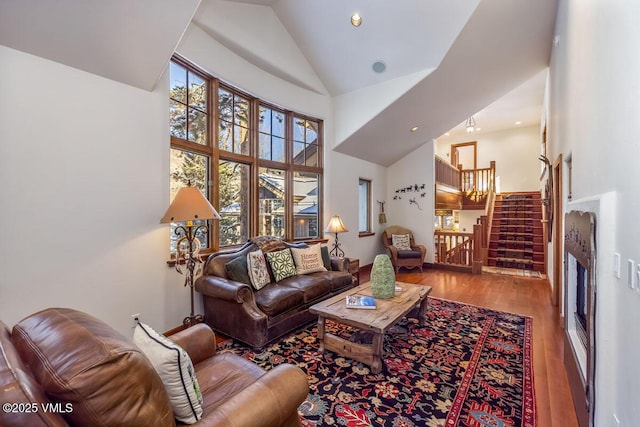 living area featuring stairway, wood finished floors, and high vaulted ceiling