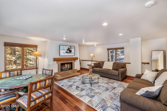 living area with a wealth of natural light, a tiled fireplace, and wood finished floors