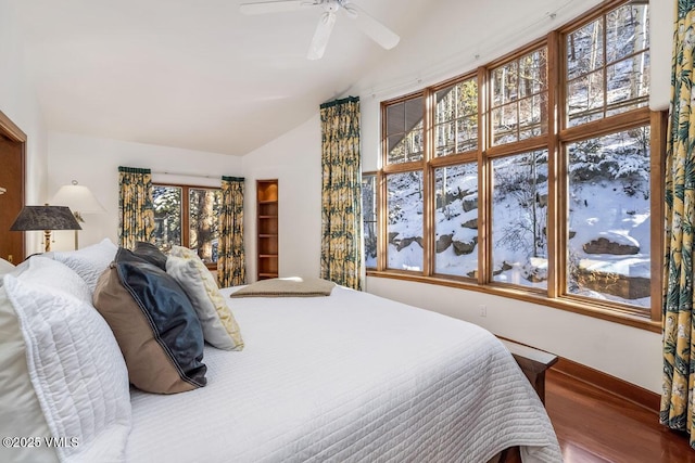 bedroom with ceiling fan, wood finished floors, and vaulted ceiling