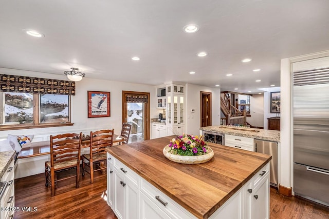 kitchen with butcher block countertops, recessed lighting, dark wood-type flooring, and built in fridge