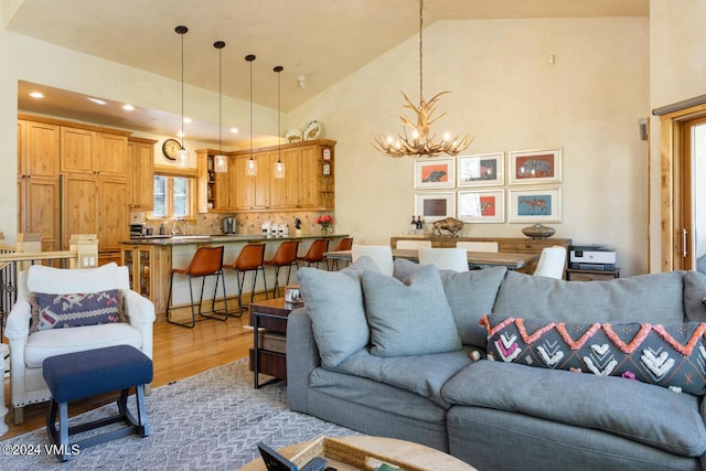 living room featuring a chandelier, high vaulted ceiling, and light wood-type flooring