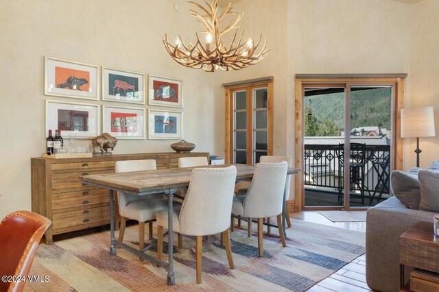 dining area featuring a high ceiling, an inviting chandelier, and light hardwood / wood-style flooring