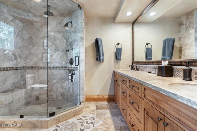 bathroom featuring an enclosed shower, vanity, and backsplash