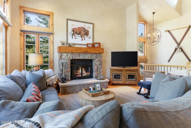 living room featuring hardwood / wood-style flooring, high vaulted ceiling, a notable chandelier, and a fireplace