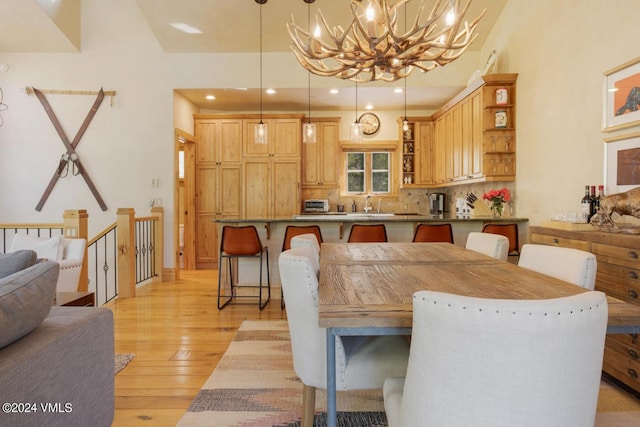 dining space with an inviting chandelier, sink, and light hardwood / wood-style flooring