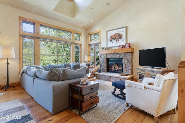 living room with a stone fireplace, high vaulted ceiling, and light hardwood / wood-style floors