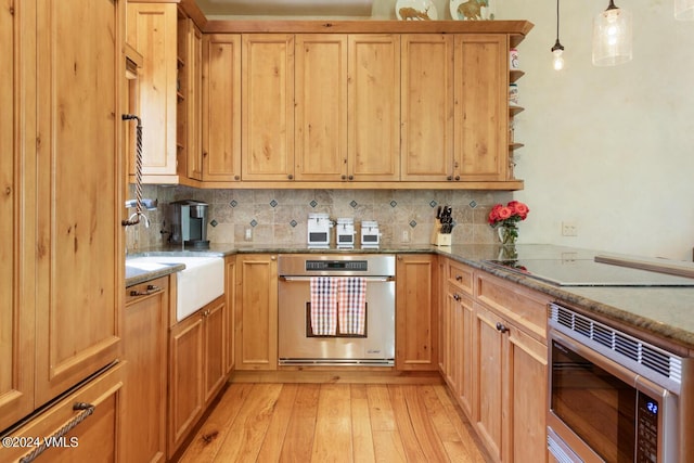 kitchen with pendant lighting, sink, stainless steel appliances, light hardwood / wood-style floors, and light stone countertops