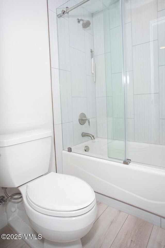 full bathroom featuring toilet, bath / shower combo with glass door, and wood finished floors