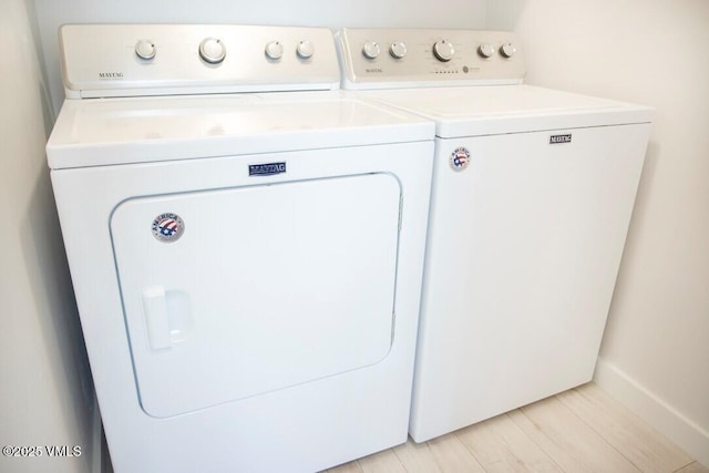 washroom with light wood-type flooring, laundry area, and washing machine and clothes dryer