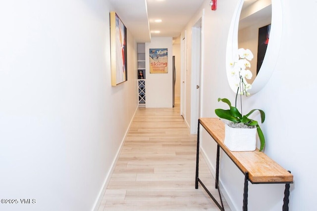 hall featuring light wood-style floors and baseboards