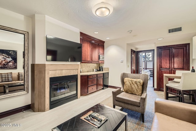 living room featuring a fireplace, light hardwood / wood-style floors, and a textured ceiling